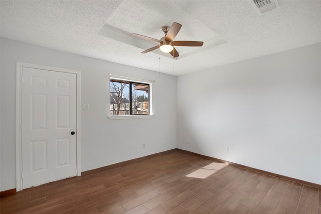 unfurnished room with ceiling fan, dark hardwood / wood-style flooring, and a textured ceiling