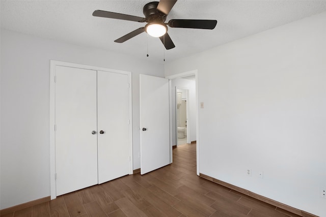 unfurnished bedroom with dark wood-type flooring, ceiling fan, a closet, and a textured ceiling