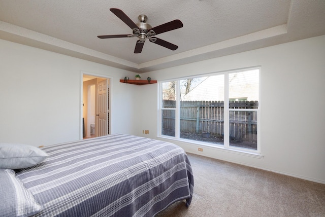 carpeted bedroom featuring a tray ceiling and a textured ceiling