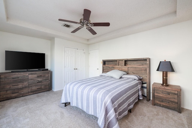 carpeted bedroom with ceiling fan, a raised ceiling, and a textured ceiling