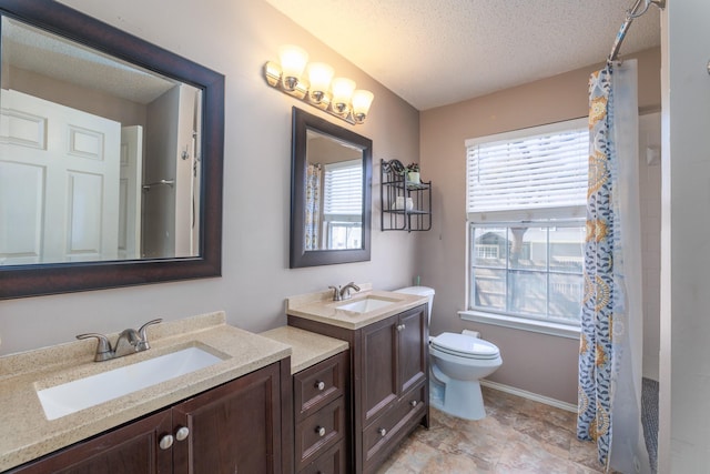 bathroom with vanity, plenty of natural light, a textured ceiling, and toilet