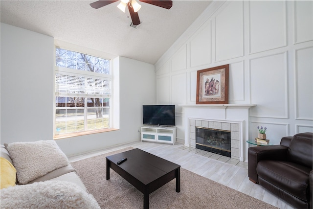 living room with lofted ceiling, light hardwood / wood-style floors, a tile fireplace, and a wealth of natural light