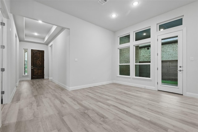 entrance foyer featuring a tray ceiling, light wood-type flooring, visible vents, baseboards, and recessed lighting