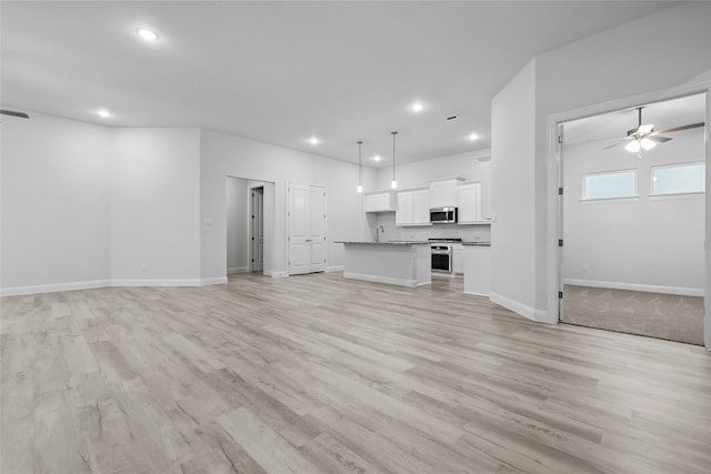 unfurnished living room featuring a ceiling fan, light wood finished floors, recessed lighting, and a sink
