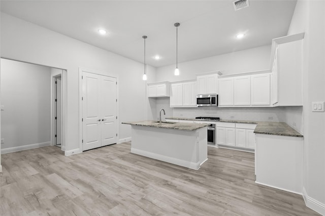kitchen with white cabinetry, a sink, visible vents, and stainless steel microwave