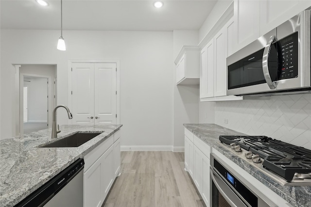 kitchen with a sink, stainless steel appliances, white cabinetry, and decorative backsplash