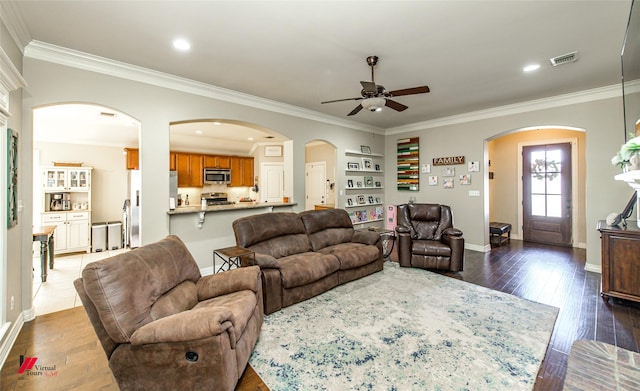 living room featuring built in shelves, ceiling fan, ornamental molding, and dark hardwood / wood-style flooring