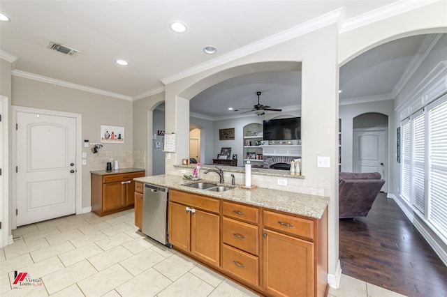 kitchen with dishwasher, sink, ceiling fan, light stone counters, and crown molding