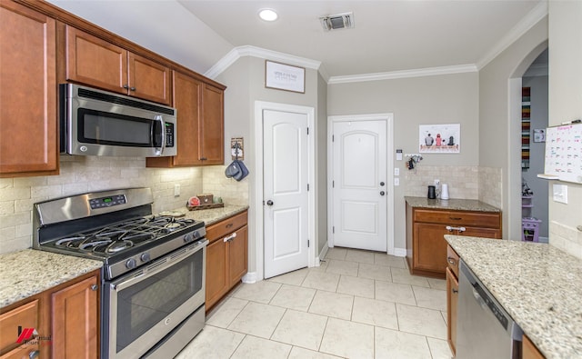 kitchen with tasteful backsplash, crown molding, appliances with stainless steel finishes, and light stone counters