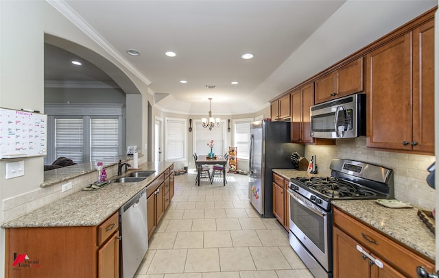 kitchen featuring light stone countertops, ornamental molding, stainless steel appliances, and sink