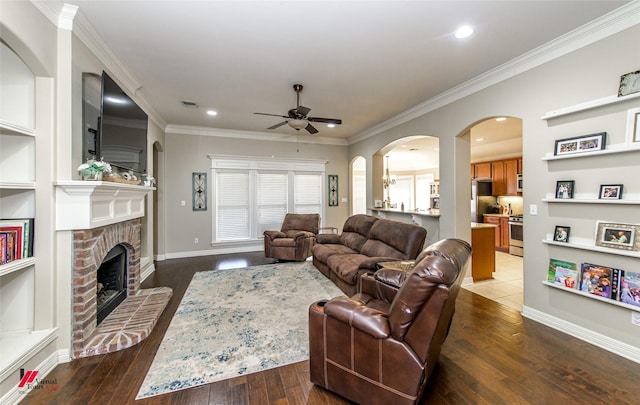 living room featuring crown molding, a fireplace, dark hardwood / wood-style floors, and ceiling fan