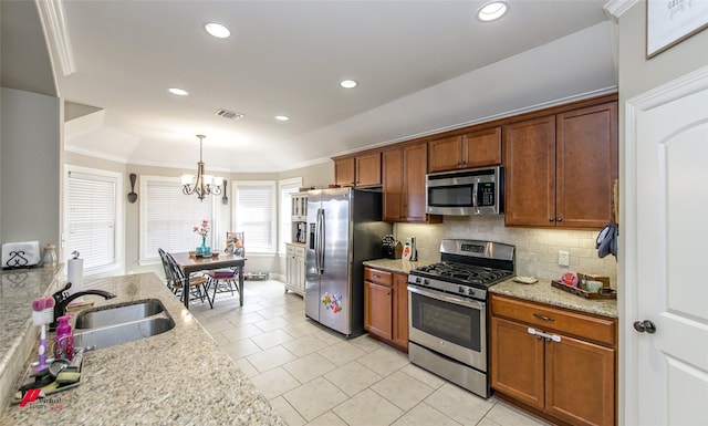 kitchen featuring appliances with stainless steel finishes, sink, pendant lighting, and light stone counters