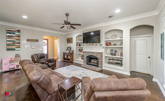 living room with crown molding, dark wood-type flooring, a fireplace, and built in shelves