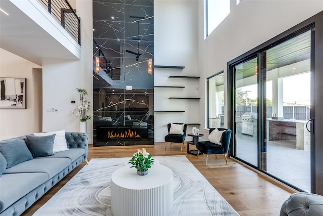 living room with a high ceiling, hardwood / wood-style floors, and a high end fireplace