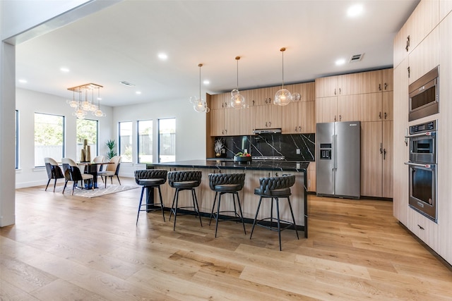 kitchen featuring decorative light fixtures, stainless steel appliances, and light brown cabinets