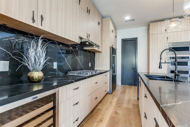 kitchen with wine cooler, sink, light brown cabinets, appliances with stainless steel finishes, and pendant lighting