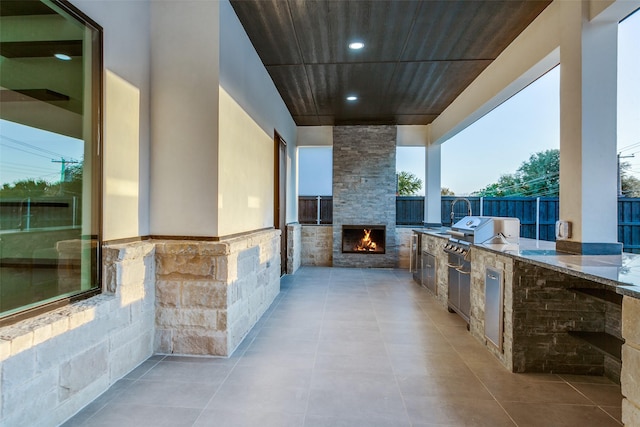 view of patio / terrace featuring a grill, an outdoor stone fireplace, and an outdoor kitchen