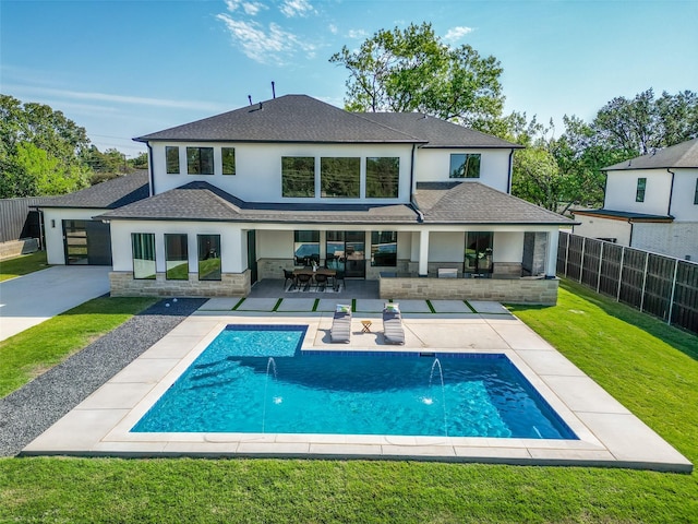 back of property featuring a fenced in pool, pool water feature, a patio area, and a lawn