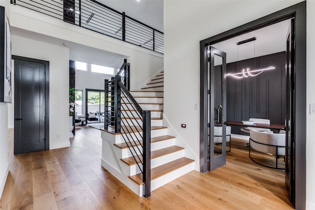 stairs with a towering ceiling, elevator, and hardwood / wood-style flooring