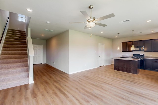 714 Gentle Bird Dr, Lavon, TX 75166 - kitchen with black microwave, gas stove, open floor plan, light wood-style floors, and baseboards