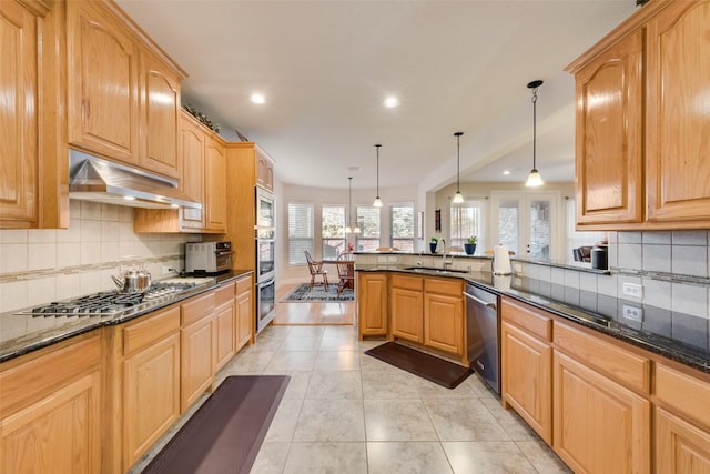 kitchen featuring sink, decorative light fixtures, dark stone countertops, appliances with stainless steel finishes, and kitchen peninsula