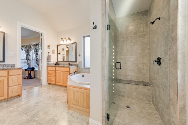 bathroom with tile patterned flooring, shower with separate bathtub, vaulted ceiling, and vanity