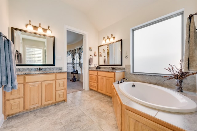 bathroom with lofted ceiling, vanity, tile patterned flooring, and a tub