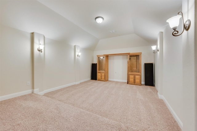 interior space with vaulted ceiling and light carpet