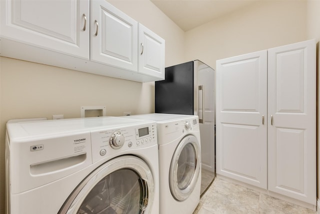 washroom with washer and dryer and cabinets