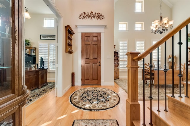 foyer entrance with a towering ceiling, light hardwood / wood-style flooring, and a chandelier