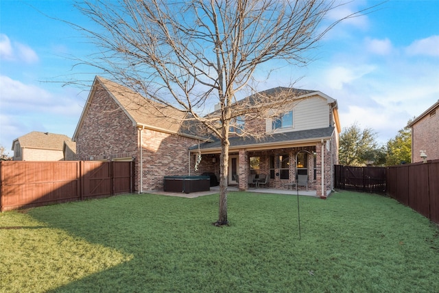 rear view of property with a patio area, a hot tub, and a lawn