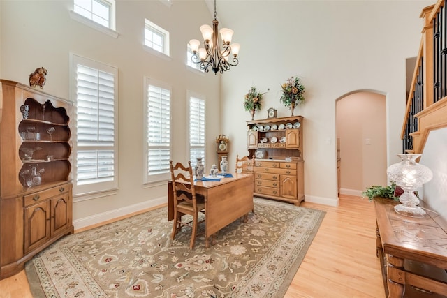 home office featuring a chandelier, light hardwood / wood-style flooring, and a high ceiling