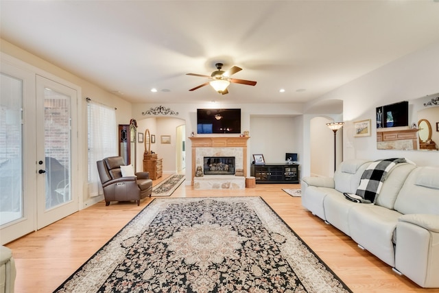 living room with french doors, ceiling fan, and light wood-type flooring