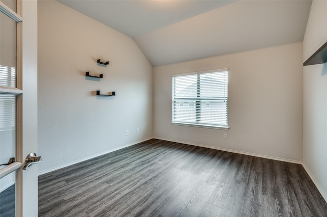 empty room featuring vaulted ceiling, baseboards, and dark wood finished floors