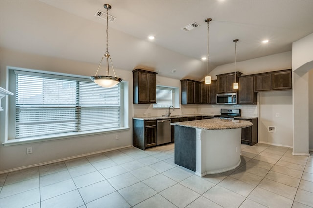 kitchen featuring dark brown cabinetry, appliances with stainless steel finishes, light stone counters, vaulted ceiling, and light tile patterned flooring