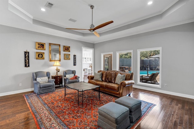 living area featuring a tray ceiling, dark wood-type flooring, visible vents, and baseboards