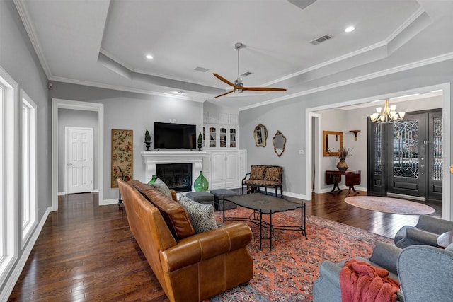 living room featuring ornamental molding, a raised ceiling, dark wood-style flooring, and a glass covered fireplace