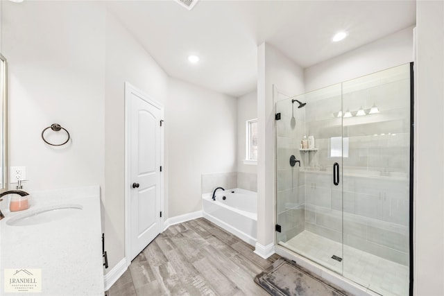 bathroom with hardwood / wood-style flooring, shower with separate bathtub, and vanity