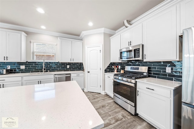 kitchen featuring sink, tasteful backsplash, ornamental molding, appliances with stainless steel finishes, and white cabinets