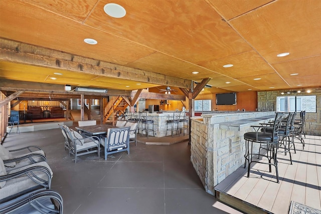 interior space with a stone fireplace, wooden ceiling, concrete floors, and ceiling fan