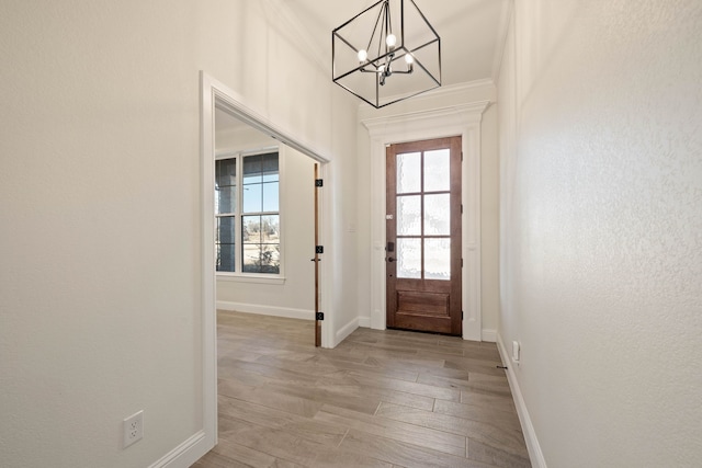 doorway to outside with a notable chandelier, crown molding, and light hardwood / wood-style floors