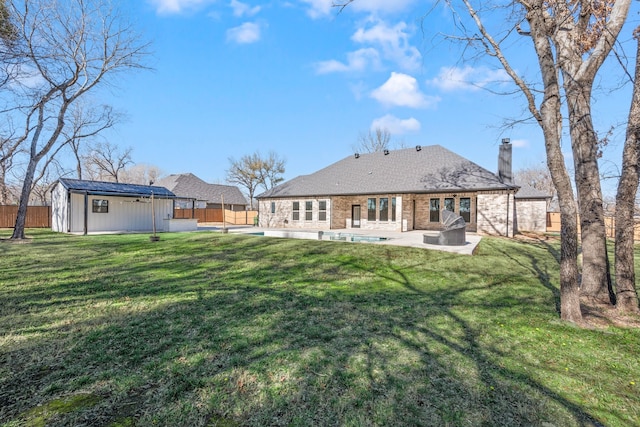 back of house with a yard, an outbuilding, and a patio area