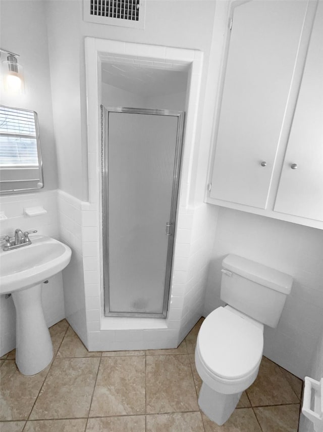 bathroom featuring tile patterned flooring, tile walls, an enclosed shower, and toilet