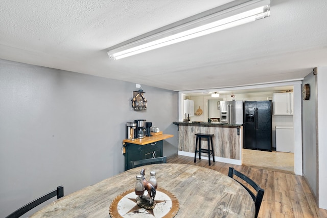 dining space with light hardwood / wood-style flooring and a textured ceiling