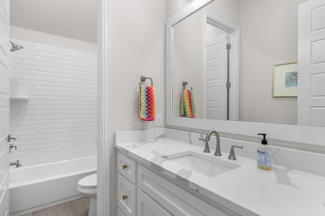 full bathroom featuring hardwood / wood-style flooring, vanity, tiled shower / bath, and toilet