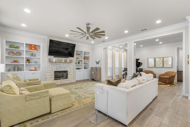 living room featuring ceiling fan, a stone fireplace, crown molding, and light wood-type flooring