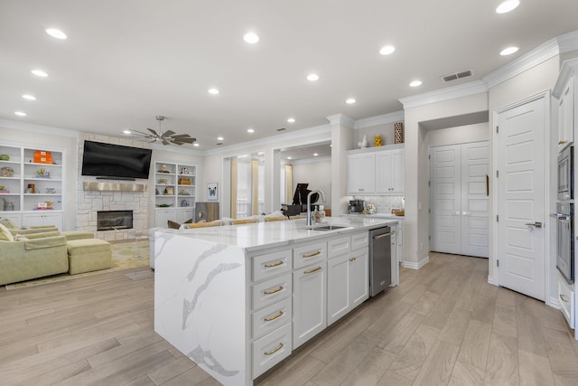 kitchen with light stone counters, sink, an island with sink, and white cabinets