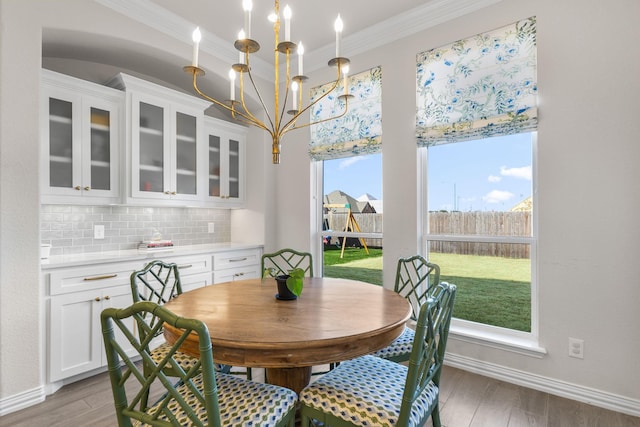 dining room with a notable chandelier, light hardwood / wood-style flooring, and ornamental molding