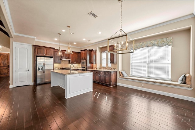 kitchen featuring appliances with stainless steel finishes, a kitchen island with sink, sink, and decorative light fixtures