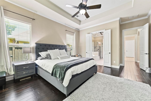 bedroom featuring a raised ceiling, ornamental molding, connected bathroom, and dark hardwood / wood-style flooring